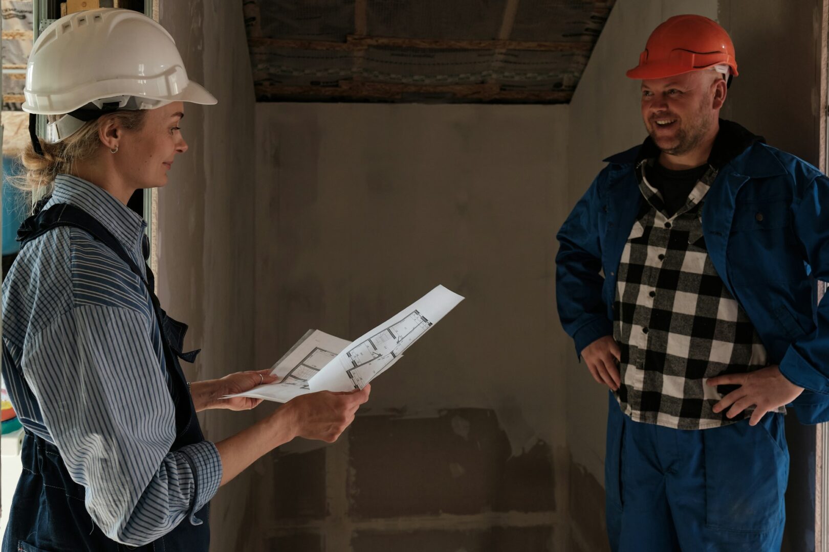 a-man-and-a-woman-in-hardhats-looking-at-a-blueprint